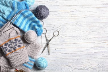 Beyaz ahşap arka planda düz örgü ve kış aksesuarları.