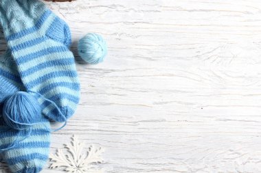 Beyaz ahşap arka planda düz örgü ve kış aksesuarları.