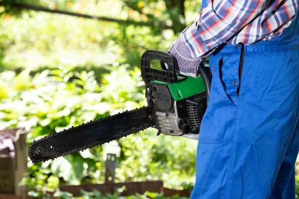 A worker holds a petrol hand saw in his hands