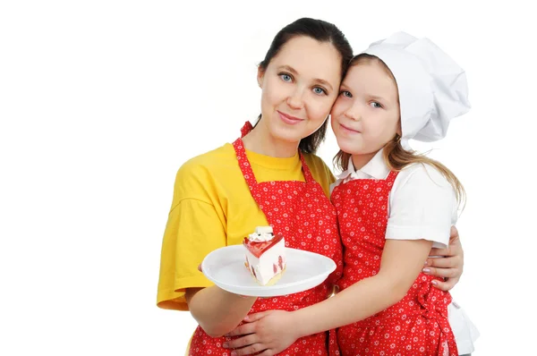 Mother holding a plate with cake hugging her daughter — Stock Photo, Image