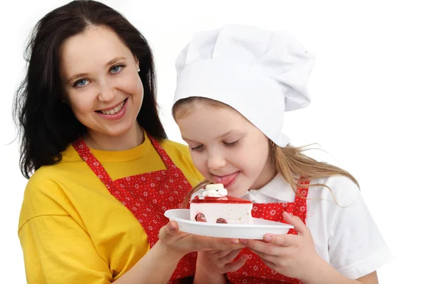 Mother holding a plate with cake hugging her daughter — Stock Photo, Image