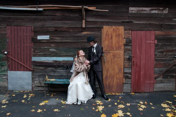 Mariée assise sur le banc tenant des coussins avec un marié — Photo