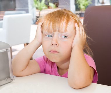 küçük kız bir masaya oturur.