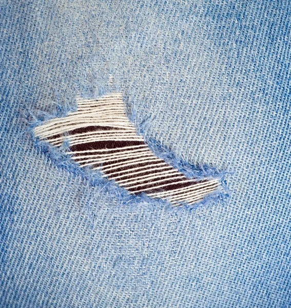 Textura de jean azul con un agujero —  Fotos de Stock