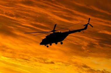 Günbatımı arka planında helikopter silueti. Gökyüzünde helikopter.