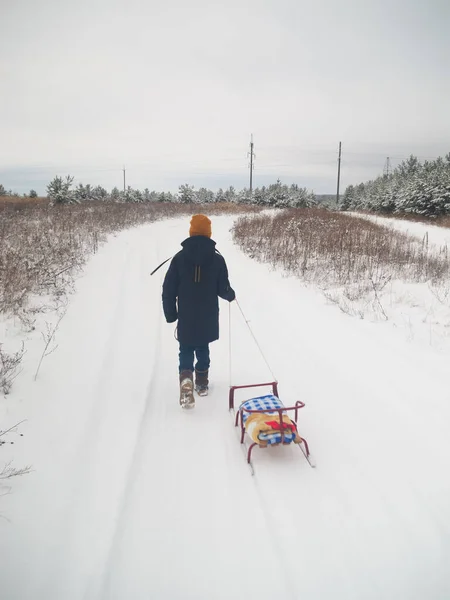 带着雪橇在冬天的森林里散步的男孩 — 图库照片