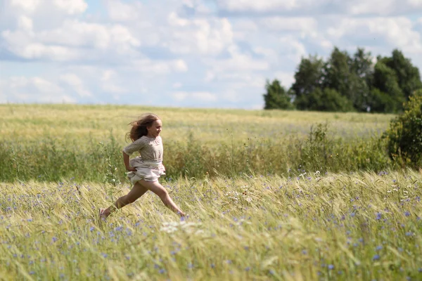 Baby girl in a long dress in the middle of the field laughing — Stock Photo, Image