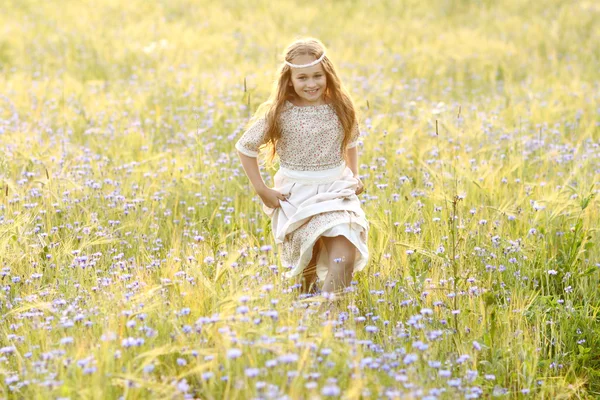 Bebê menina em um vestido longo no meio do campo rindo — Fotografia de Stock