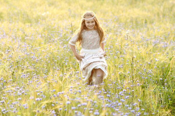 Baby girl in a long dress in the middle of the field laughing