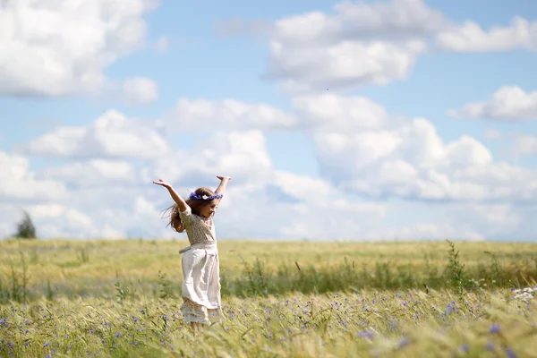 Baby girl in a long dress in the middle of the field laughing — Stock Photo, Image