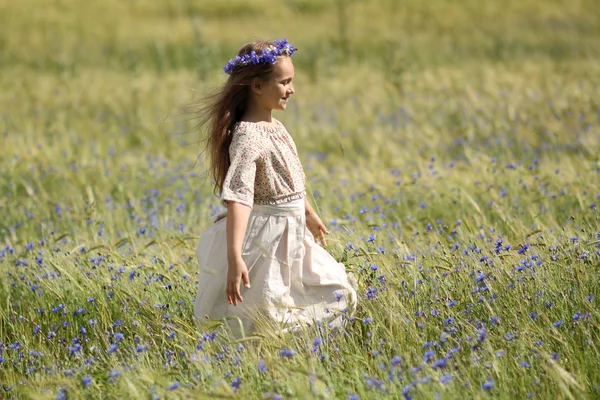 Baby girl in a long dress in the middle of the field laughing — Stock Photo, Image