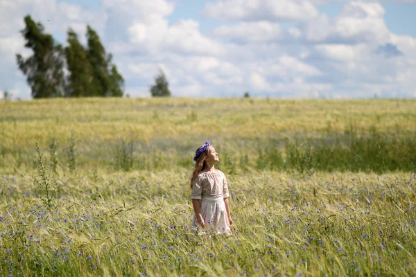 Baby girl in a long dress in the middle of the field laughing — Stock Photo, Image