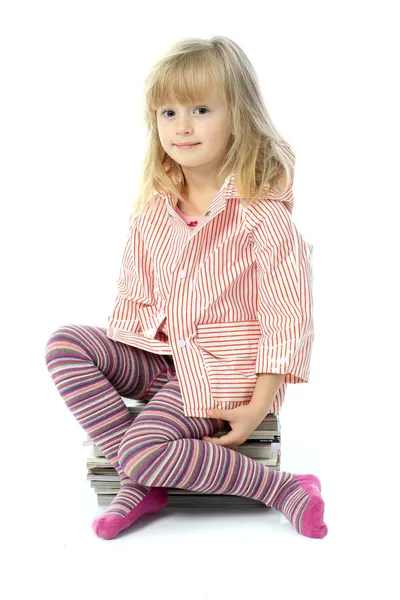 Girl sitting on a stack of magazines Royalty Free Stock Photos