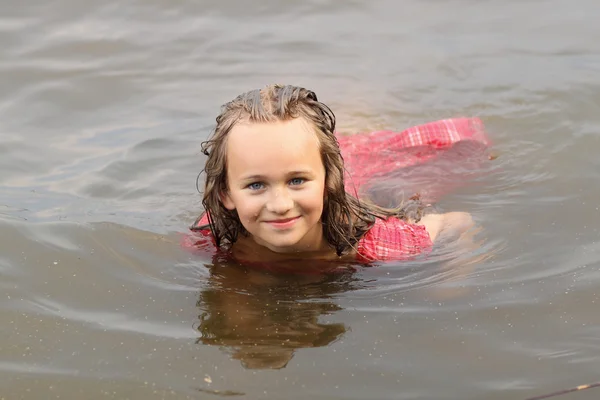 Beautiful emotional girl child in dress swims in the water — Stock Photo, Image