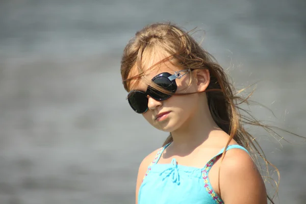 Portrait of a child girl wearing sunglasses with developing hair in the wind — Stock Photo, Image