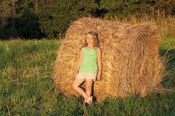 Привлекательная девочка рядом со стопкой соломы — стоковое фото