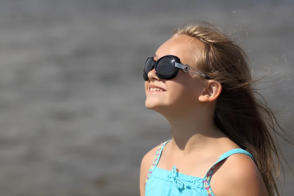 Portrait of a child girl wearing sunglasses with developing hair in the wind — Stock Photo, Image