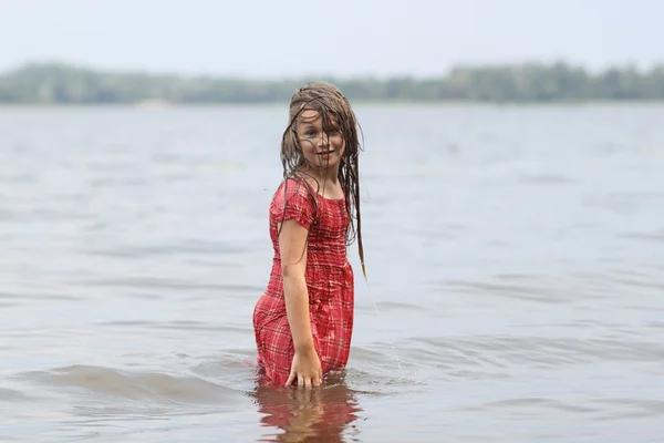 Beautiful emotional girl child in dress swims in the water — Stock Photo, Image