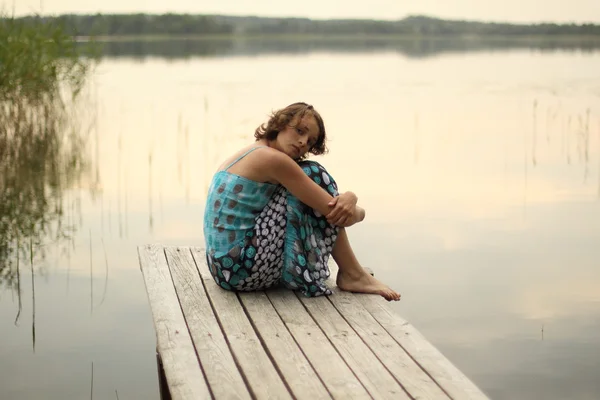 Schönes Mädchen sitzt auf Pier — Stockfoto