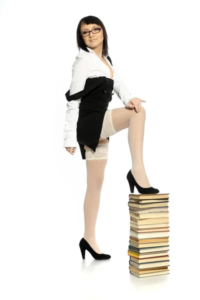 Chica atractiva vestida con medias eróticas apoyada en una pila de libros — Foto de Stock