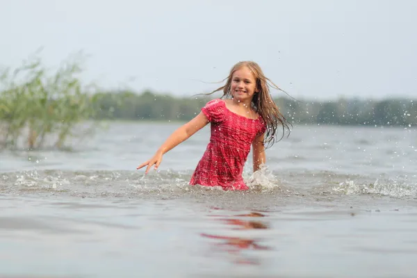 Beautiful emotional girl child in dress swims in the water — Stock Photo, Image