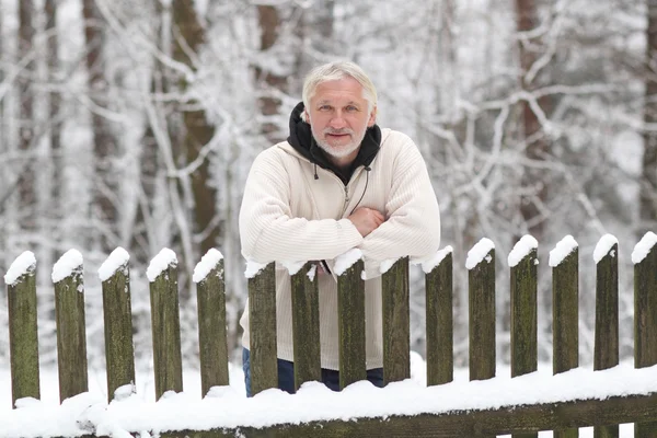 Рядом с забором стоит привлекательный седой мужчина средних лет — стоковое фото