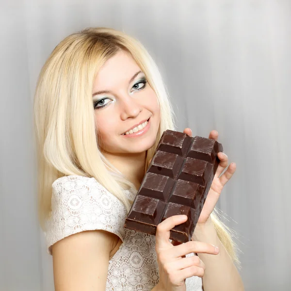 Agradable chica rubia linda natural comiendo una gran barra de chocolate — Foto de Stock