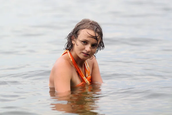 橘红色衣服的年轻女孩在水中则涉猎 — 图库照片