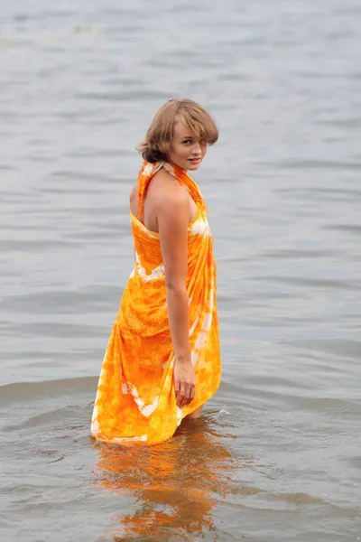 Teen girl in orange dress in water — Stock Photo, Image