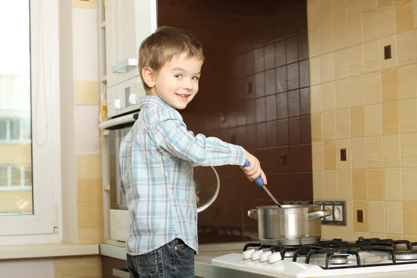 Mały chłopiec gotowanie w pobliżu pieca gazowego — Zdjęcie stockowe
