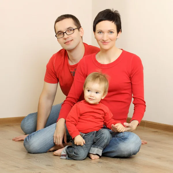 Família feliz em jeans e camisas vermelhas — Fotografia de Stock