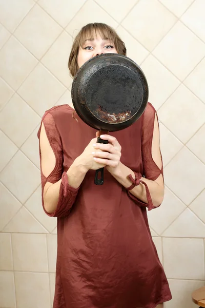 Angry attractive girl in evening dress holding a frying pan — Stock Photo, Image