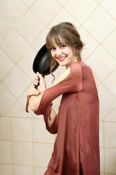 Angry attractive girl in evening dress holding a frying pan — Stock Photo, Image