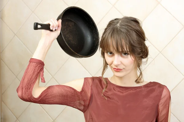 Angry attractive girl in evening dress holding a frying pan — Stock Photo, Image