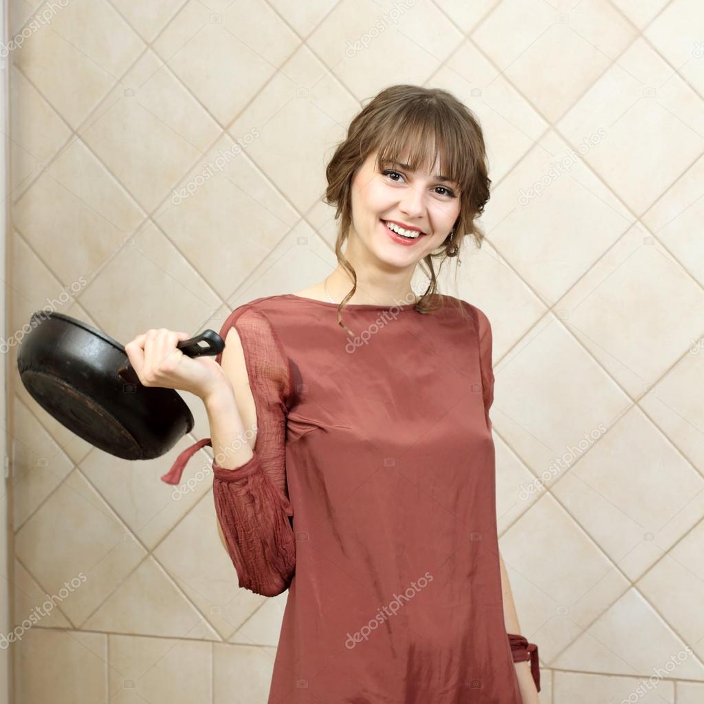 Angry attractive girl in evening dress holding a frying pan