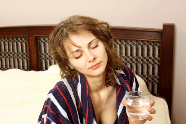 Eine Frau im Bademantel leidet unter Kopfschmerzen — Stockfoto