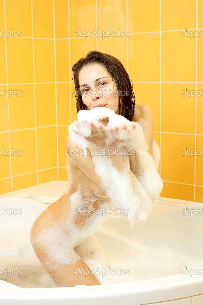 Positive slender girl indulges in a bath with foam