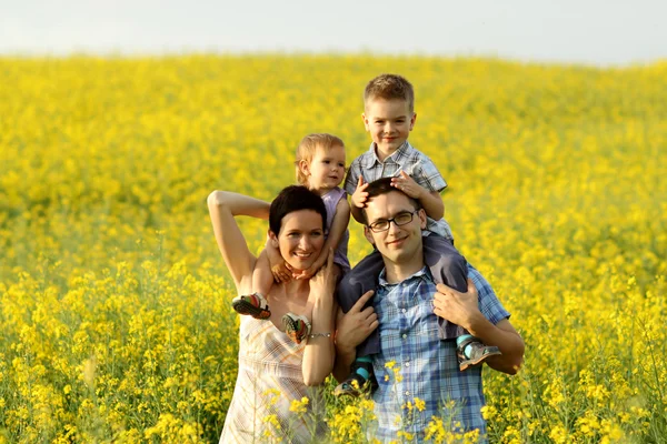 Família feliz de quatro em um campo — Fotografia de Stock