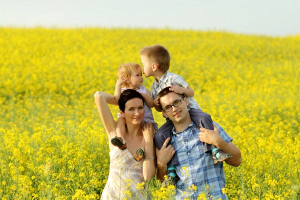 Lycklig familj av fyra i ett fält — Stockfoto