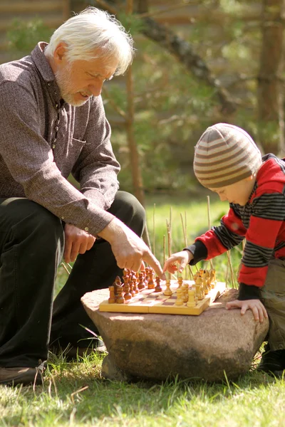 Дедушка и внук играют в шахматы — стоковое фото