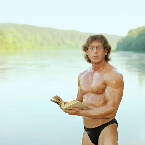 美丽的裸体健美男人在海滩上的阅读 — 图库照片