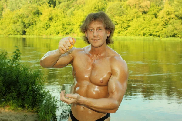 Homme modèle de remise en forme bodybuilder presse le jus d'orange dans un verre — Photo