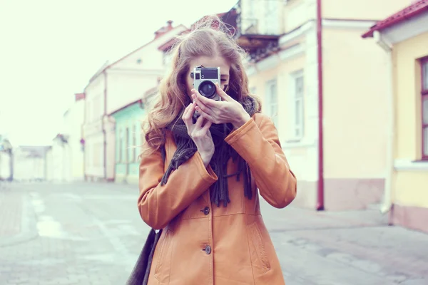 Девушка со старым фотоаппаратом прогуливается по старинным улицам — стоковое фото