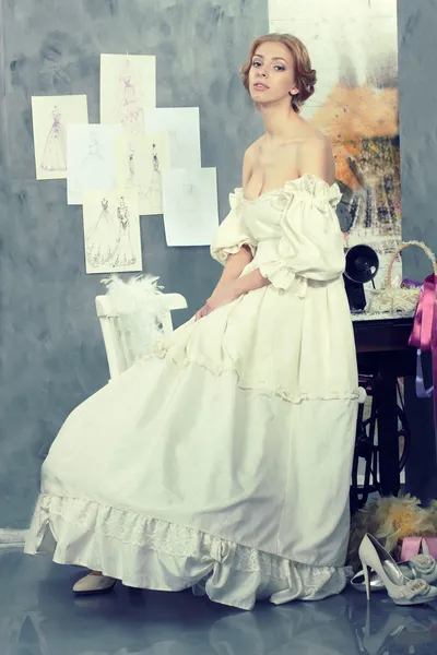 Hermosa mujer en vestido vintage está en estudio de diseño de ropa — Foto de Stock
