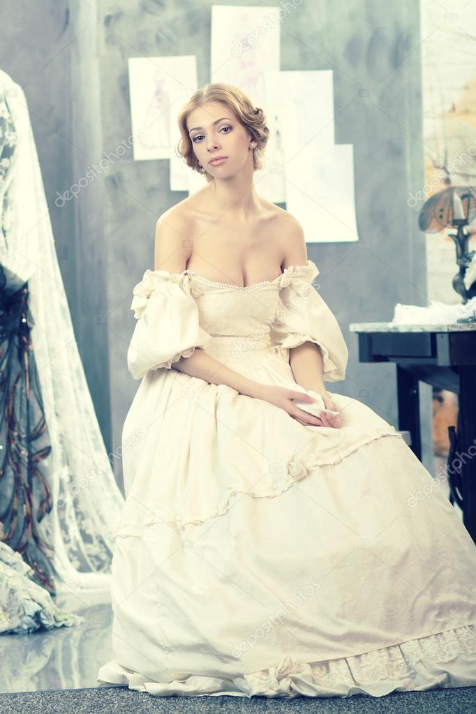 Beautiful woman in vintage dress is in clothing design studio