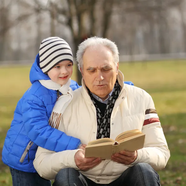 Abuelo y nieto leyendo un libro al aire libre — Foto de Stock