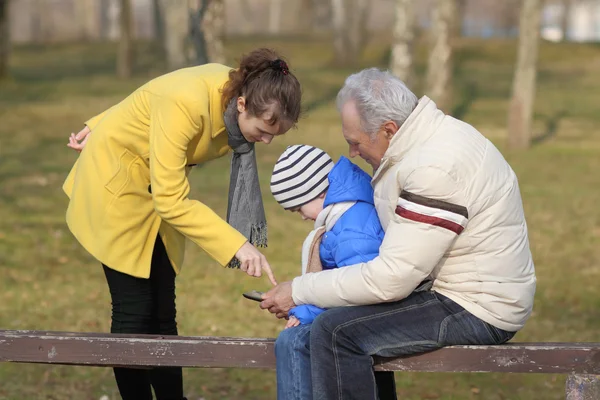 Grandfather and grandson are looking tablet on bench outdoors — Stock Photo, Image