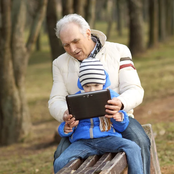 祖父と孫の屋外ベンチにタブレットを探しています。 — ストック写真