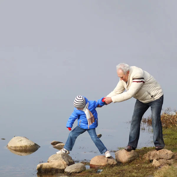 Abuelo y nieto en piedras cerca del agua —  Fotos de Stock