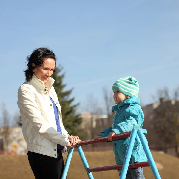 Молодая мама занимается фитнесом с маленькой дочкой на детской площадке — стоковое фото